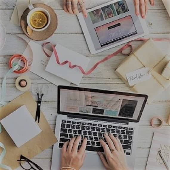 Deux personnes travaillent sur un bureau encombré de materiel de type scrapbooking